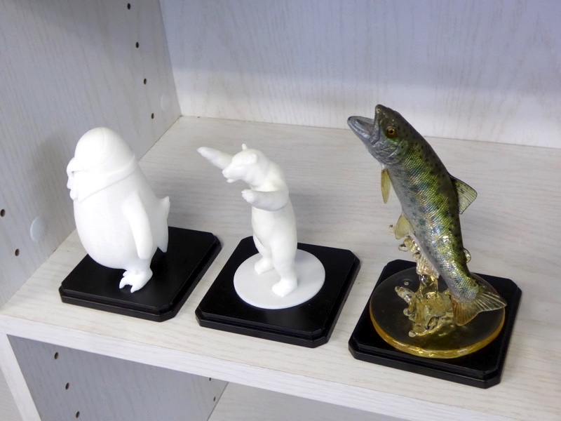 棚には3Dプリンターで制作したキャラクター(左・中)。右はシリコン、レジンで作成したリアルな魚です。魚（ヤマメ）はイラストレーターの西村昌実先生の作品です。
